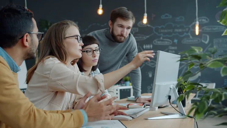 Kolleginnen und Kollegen arbeiten im Büro zusammen am Laptop